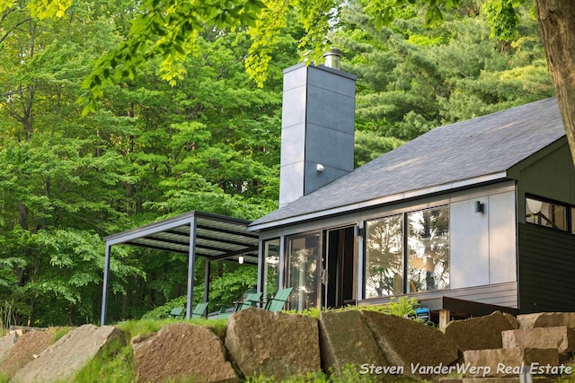 5185 W Nurnberg Rd, Michigan, MI 49411 - back of property featuring a chimney, a forest view, and a shingled roof