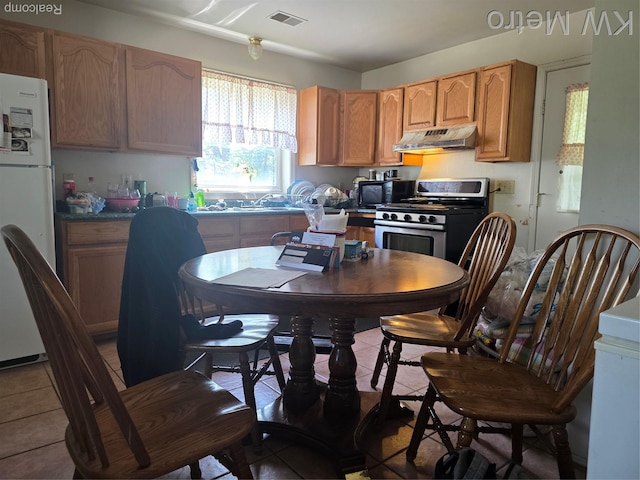 29827 Oakwood St, Inkster, MI 48141 - kitchen featuring stainless steel range with gas stovetop, freestanding refrigerator, under cabinet range hood, black microwave, and tile patterned floors