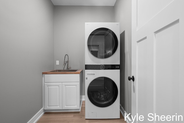 8060 Hunters Xing, Kalamazoo, MI 49009 - laundry room featuring stacked washing machine and dryer, light wood finished floors, cabinet space, and baseboards