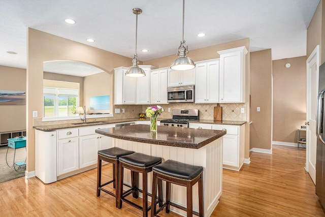 1300 St Andrews Dr, Holland, MI 49423 - kitchen with appliances with stainless steel finishes, a sink, a breakfast bar, light wood finished floors, and recessed lighting