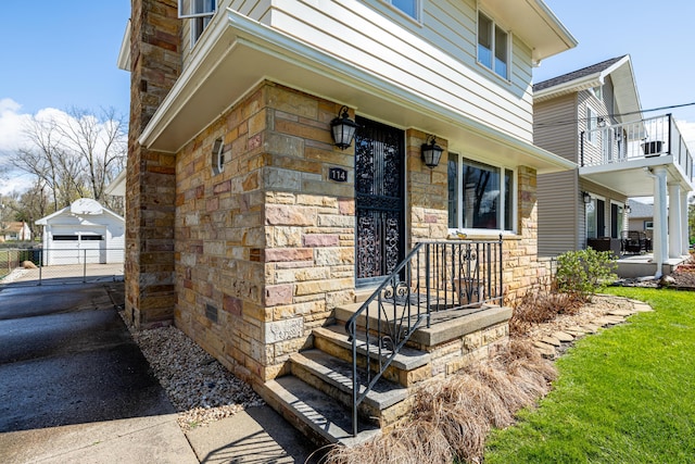 114 W Grove Ave, Michigan Center, MI 49254 - doorway to property featuring stone siding, a detached garage, and asphalt driveway