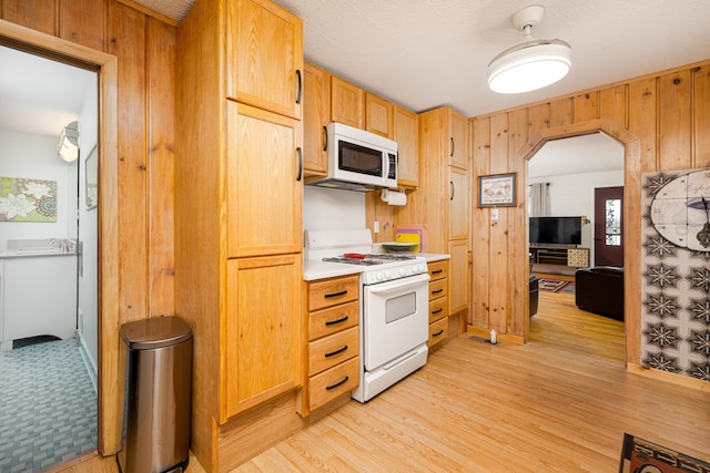 114 W Grove Ave, Michigan Center, MI 49254 - kitchen featuring white appliances, arched walkways, light wood-type flooring, wooden walls, and light countertops
