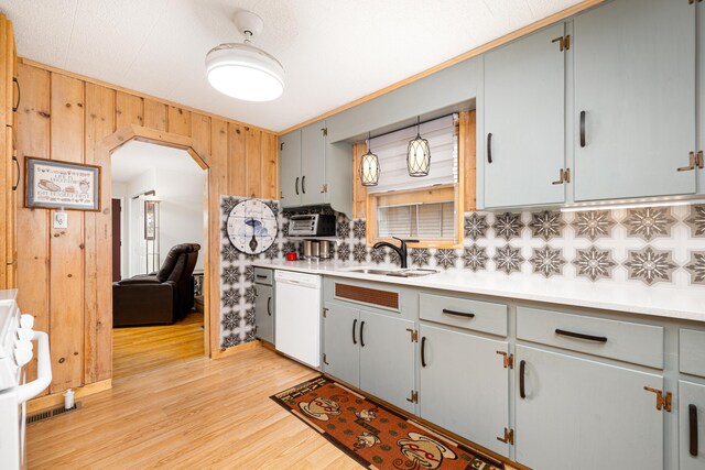 114 W Grove Ave, Michigan Center, MI 49254 - kitchen featuring white dishwasher, a sink, decorative backsplash, light countertops, and light wood-style flooring