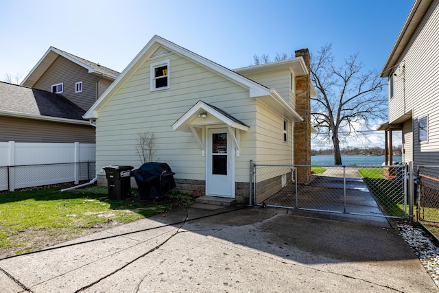 114 W Grove Ave, Michigan Center, MI 49254 - rear view of property with a gate, a chimney, driveway, and a water view