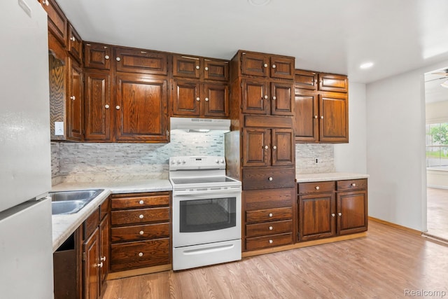 1496 E Parkwood Ave, Burton, MI 48529 - kitchen featuring white appliances, under cabinet range hood, light wood-style flooring, tasteful backsplash, and light countertops