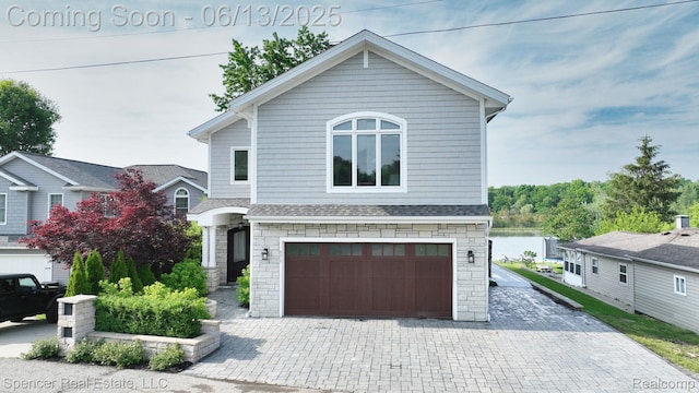571 Dunleavy Dr, Highland, MI 48356 - view of front of house featuring decorative driveway, a garage, stone siding, and a shingled roof