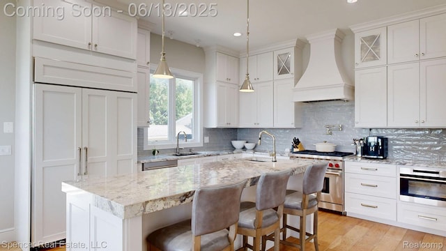 571 Dunleavy Dr, Highland, MI 48356 - kitchen featuring stainless steel appliances, premium range hood, a sink, tasteful backsplash, and a kitchen island with sink