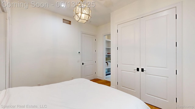 571 Dunleavy Dr, Highland, MI 48356 - bedroom with a closet, a chandelier, and light wood-style floors