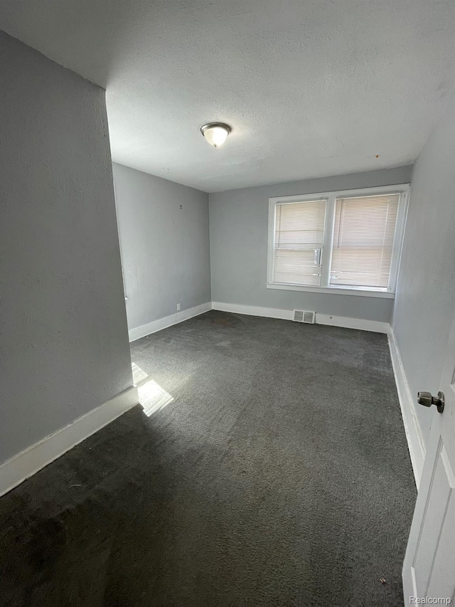 4368 Buckingham Ave, Detroit, MI 48224 - unfurnished room featuring dark colored carpet, baseboards, and a textured ceiling