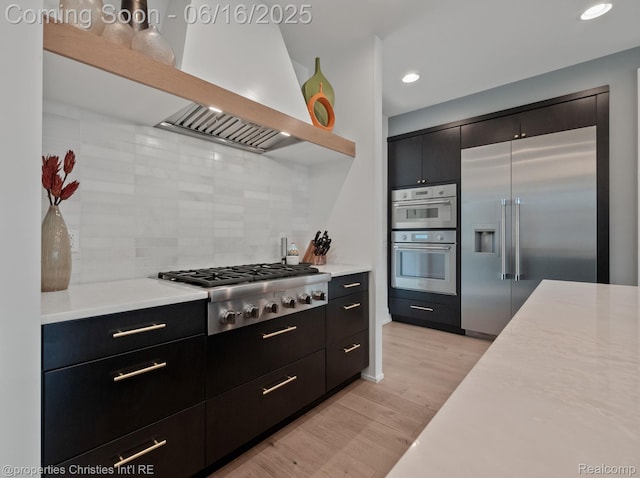1044 Hazel, Birmingham, MI 48009 - kitchen featuring wall chimney exhaust hood, appliances with stainless steel finishes, open shelves, light countertops, and decorative backsplash