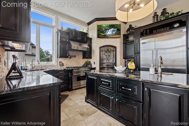 10993 Stoney Point Dr, South Lyon, MI 48178 - kitchen featuring dark cabinetry, high quality appliances, a sink, stone tile floors, and tasteful backsplash