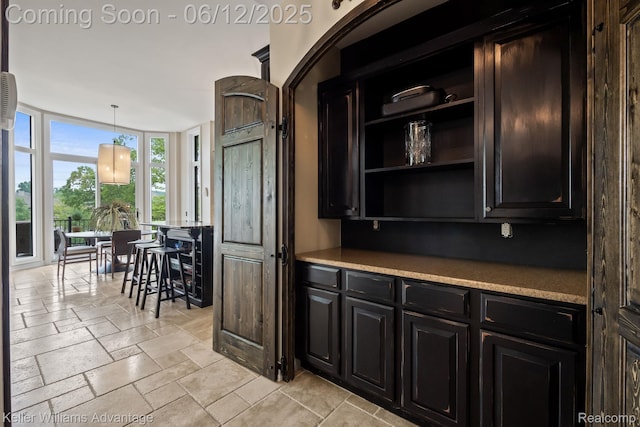 10993 Stoney Point Dr, South Lyon, MI 48178 - kitchen featuring stone tile floors, light countertops, open shelves, decorative light fixtures, and a wall of windows