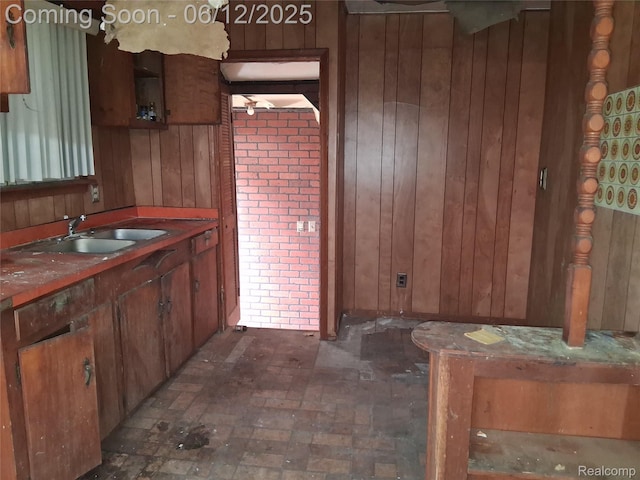 709 E Margaret St, Highland Park, MI 48203 - kitchen featuring wooden walls, a sink, brick patterned flooring, and brown cabinets