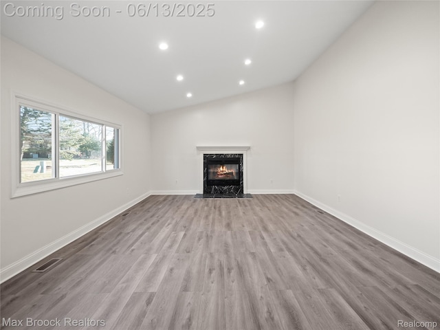 6150 Anne Dr, West Bloomfield, MI 48322 - unfurnished living room with wood finished floors, a high end fireplace, recessed lighting, vaulted ceiling, and baseboards