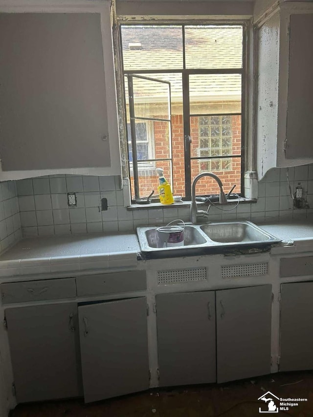15016 Troester St, Detroit, MI 48205 - kitchen with a sink, white cabinetry, decorative backsplash, and tile countertops