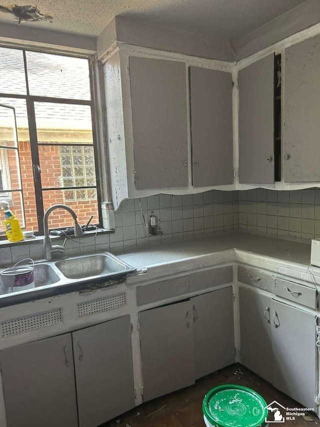 15016 Troester St, Detroit, MI 48205 - kitchen with tile countertops, backsplash, a sink, and white cabinetry
