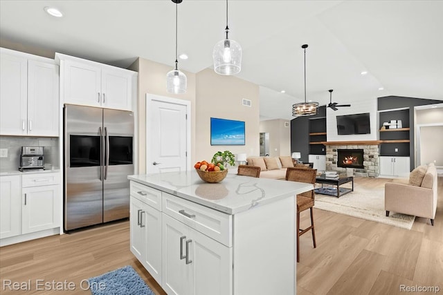 2763 Clivedon Rd, Howell, MI 48843 - kitchen with stainless steel fridge with ice dispenser, light wood-style floors, vaulted ceiling, a fireplace, and white cabinetry
