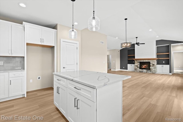 2763 Clivedon Rd, Howell, MI 48843 - kitchen with lofted ceiling, light wood finished floors, white cabinetry, pendant lighting, and a center island