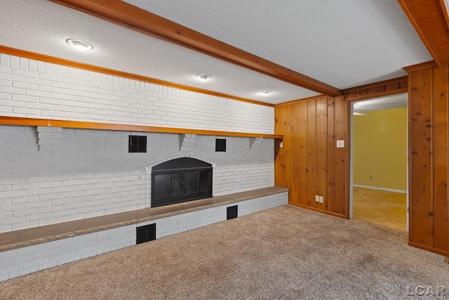 345 Alexander Dr, Adrian, MI 49221 - unfurnished living room with a textured ceiling, carpet flooring, beamed ceiling, a brick fireplace, and wood walls