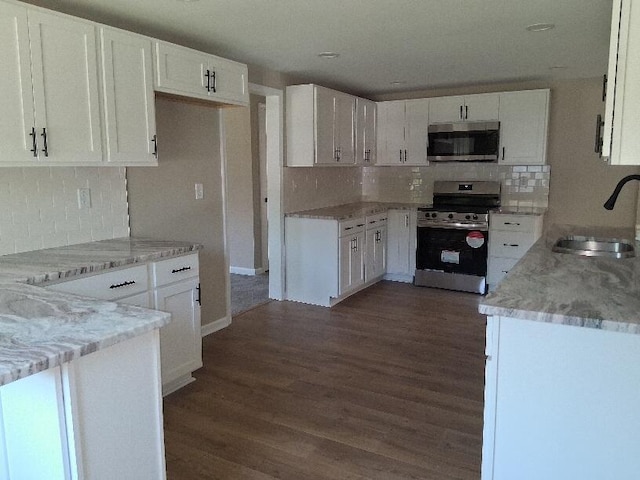 243 Lake Dr, Muskegon, MI 49441 - kitchen featuring appliances with stainless steel finishes, tasteful backsplash, dark wood-type flooring, and white cabinets