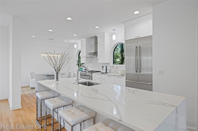 3856 Pine Lake Knoll Dr, West Bloomfield, MI 48324 - kitchen featuring stainless steel built in refrigerator, wall chimney exhaust hood, a sink, white cabinets, and a kitchen island with sink