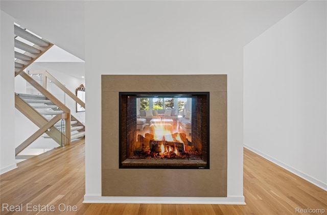 3856 Pine Lake Knoll Dr, West Bloomfield, MI 48324 - detailed view of a multi sided fireplace, wood finished floors, and baseboards