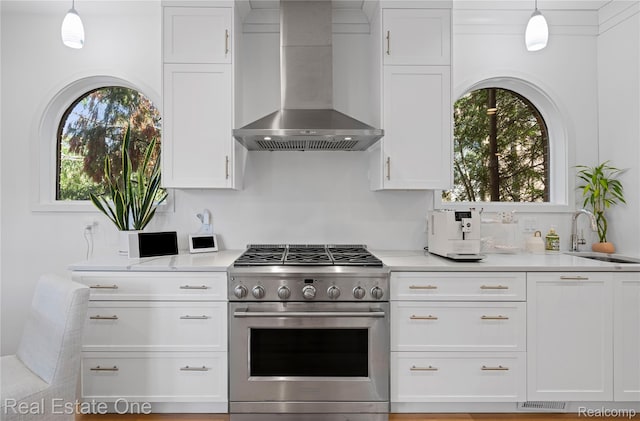 3856 Pine Lake Knoll Dr, West Bloomfield, MI 48324 - kitchen featuring wall chimney range hood, stainless steel range with gas stovetop, a sink, white cabinets, and light countertops