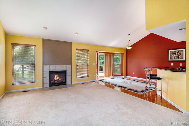 1130 Andover Cir, Commerce Twp, MI 48390 - living room featuring baseboards, a tile fireplace, carpet floors, vaulted ceiling, and wood finished floors