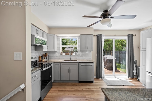 6615 Hatchery Rd, Waterford, MI 48327 - kitchen featuring stainless steel appliances, a sink, gray cabinetry, ceiling fan, and tasteful backsplash