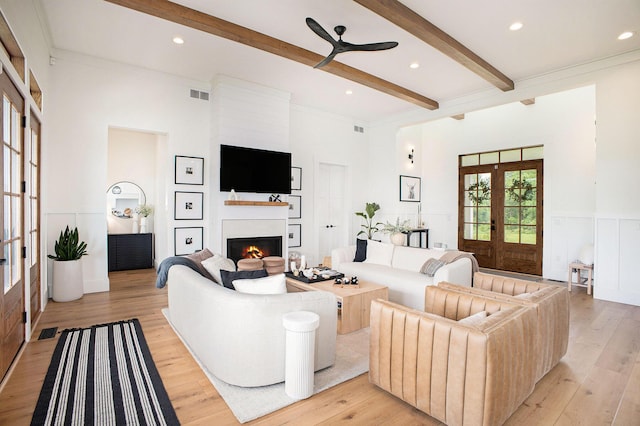 2958 S Edgar Rd, Mason, MI 48854 - living room featuring french doors, beam ceiling, a ceiling fan, a lit fireplace, and light wood-style flooring