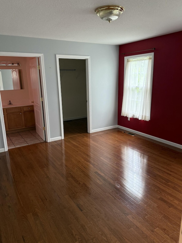12 Picardy Pl, Hillsdale, MI 49242 - unfurnished bedroom with wood finished floors, a walk in closet, and baseboards