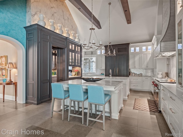 20 Hidden Rdg, Bloomfield Hills, MI 48304 - kitchen with high vaulted ceiling, high end stainless steel range, a chandelier, a kitchen island, and backsplash
