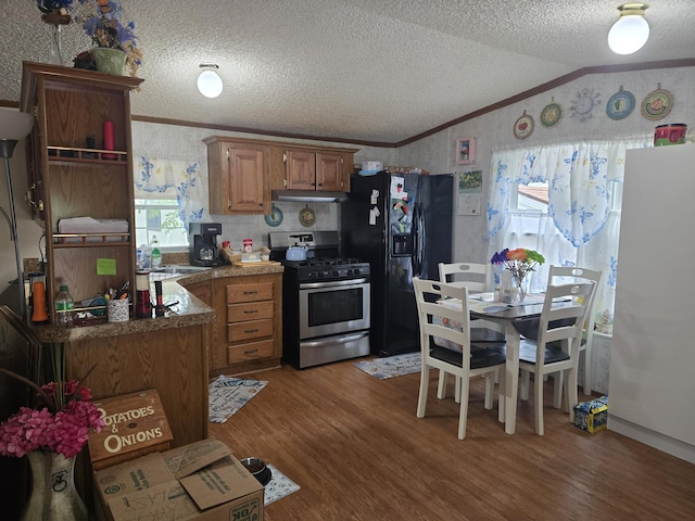 2317 Shamrock Ln, Muskegon, MI 49442 - kitchen with stainless steel gas range, wallpapered walls, black refrigerator with ice dispenser, lofted ceiling, and wood finished floors