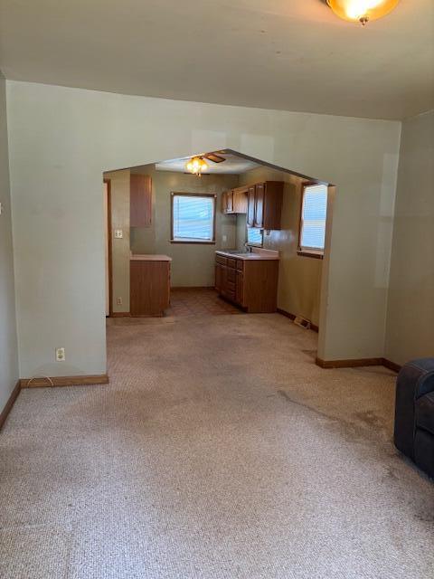 408 Hill St, Buchanan, MI 49107 - unfurnished living room featuring light carpet, baseboards, ceiling fan, and a sink