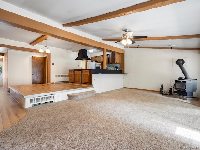 28212 Shock St, Saint Clair Shores, MI 48081 - unfurnished living room featuring radiator heating unit, a wood stove, beamed ceiling, ceiling fan, and light wood-style floors