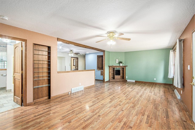 14894 L Dr N, Marshall, MI 49068 - unfurnished living room with a ceiling fan, wood finished floors, a fireplace, and a textured ceiling