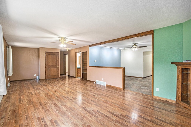 14894 L Dr N, Marshall, MI 49068 - unfurnished living room with a ceiling fan, wood finished floors, baseboards, a textured ceiling, and a textured wall