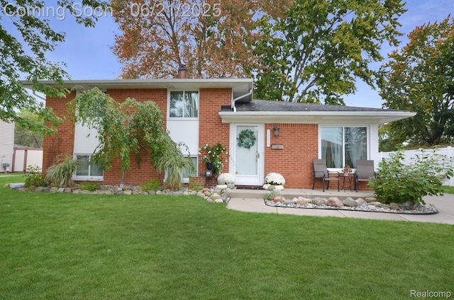 43475 Deborah Dr, Sterling Heights, MI 48313 - tri-level home with a front lawn, brick siding, a patio, and a chimney