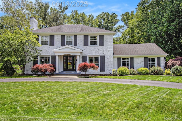 9875 Island Dr, Grosse Ile, MI 48138 - georgian-style home with brick siding, a chimney, and a front lawn