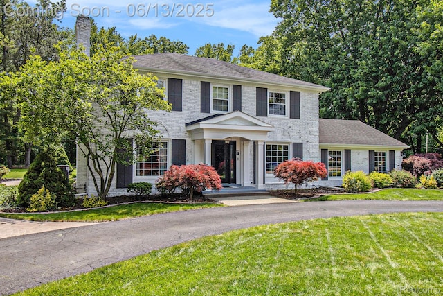 9875 Island Dr, Grosse Ile, MI 48138 - view of front facade with brick siding, a chimney, and a front lawn