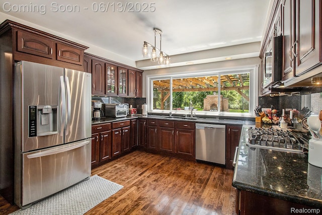 9875 Island Dr, Grosse Ile, MI 48138 - kitchen with appliances with stainless steel finishes, dark wood-type flooring, tasteful backsplash, dark stone counters, and a sink