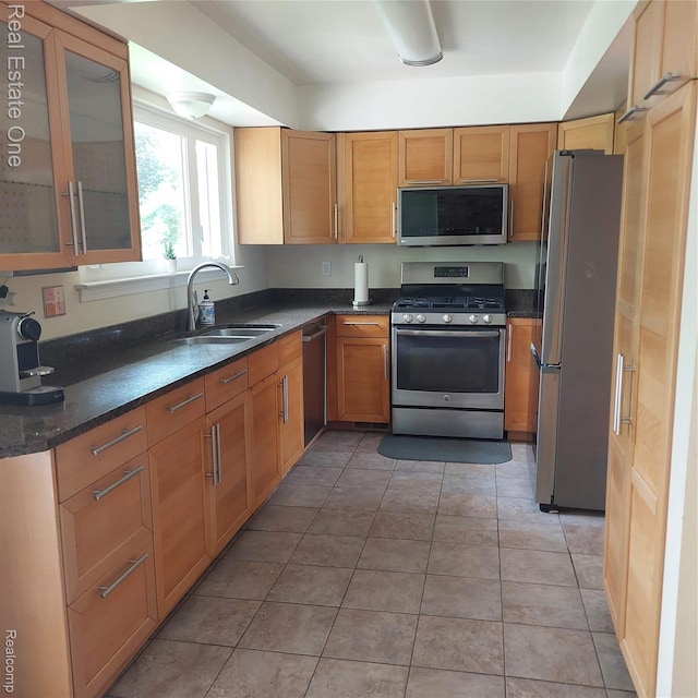 5208 Woodview Dr, Bloomfield Hills, MI 48302 - kitchen featuring stainless steel appliances, dark stone countertops, glass insert cabinets, brown cabinetry, and light tile patterned flooring
