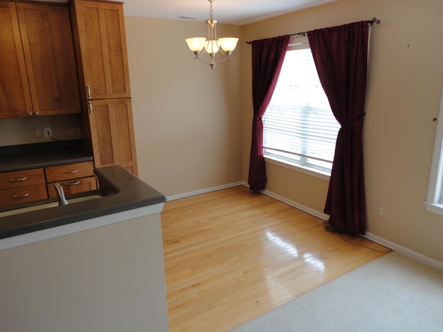 2856 Barclay Way, Ann Arbor, MI 48105 - kitchen featuring dark countertops, brown cabinets, light wood-type flooring, a chandelier, and hanging light fixtures