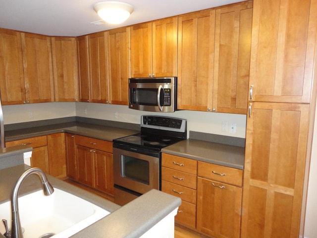2856 Barclay Way, Ann Arbor, MI 48105 - kitchen featuring stainless steel appliances, a sink, brown cabinets, and dark countertops