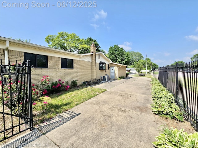 9498 Bassett St, Livonia, MI 48150 - view of property exterior featuring brick siding, a chimney, driveway, and central AC