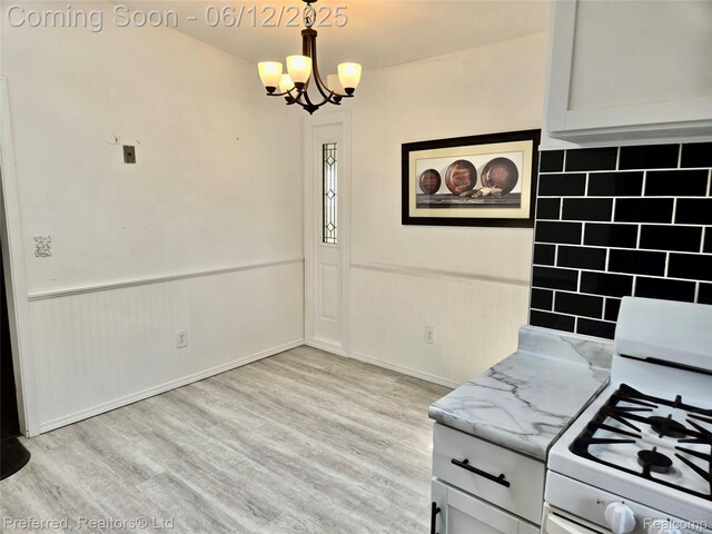 9498 Bassett St, Livonia, MI 48150 - kitchen featuring white gas range, a chandelier, wainscoting, light wood-style floors, and light stone counters