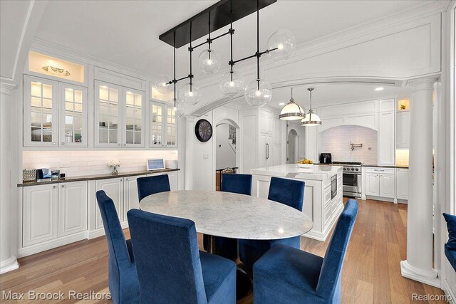 820 Hazel St, Birmingham, MI 48009 - dining room with arched walkways, light wood finished floors, ornate columns, and crown molding