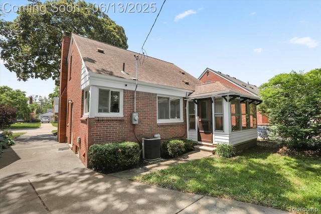 1630 N Denwood St, Dearborn, MI 48128 - rear view of house featuring brick siding, a sunroom, roof with shingles, a lawn, and a chimney