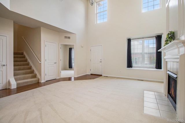 49761 Courtyard Ln, Canton, MI 48188 - unfurnished living room with a tiled fireplace, a high ceiling, carpet floors, and stairway