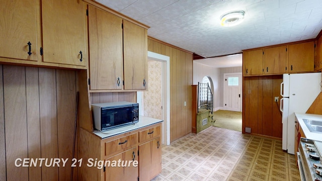107 E Johns St, Durand, MI 48429 - kitchen featuring black microwave, light countertops, freestanding refrigerator, range, and wooden walls